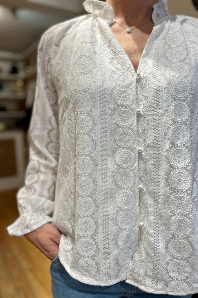 Blouse Giulia, couleur écru, manches longues resserrées sur le bas, matière broderie, encolure V, patte de boutonnage sur le devant