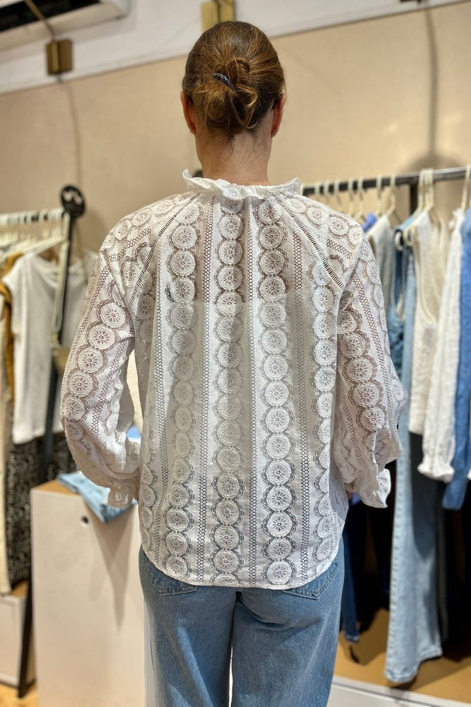 Blouse Giulia, couleur écru, manches longues resserrées sur le bas, matière broderie, encolure V, patte de boutonnage sur le devant